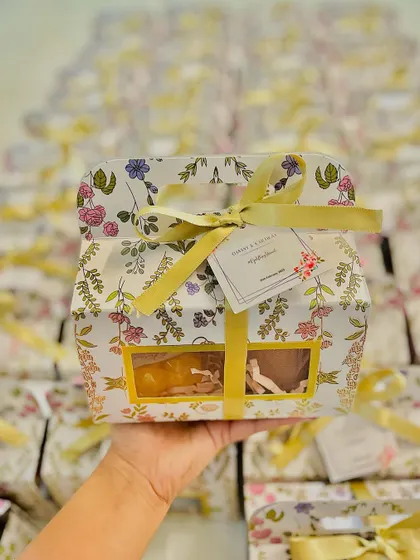 A single floral wedding favor box, held up to show the beautiful design and custom tag.