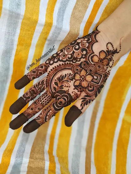 A beautiful floral design on a yellow striped background. The colours work so well together and make the henna pop.