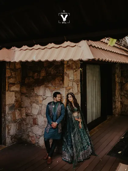 A duplicate of image 21, this portrait shows a couple sharing a look while standing on the wooden porch of a rustic stone cottage, blending elegant attire with a natural setting.