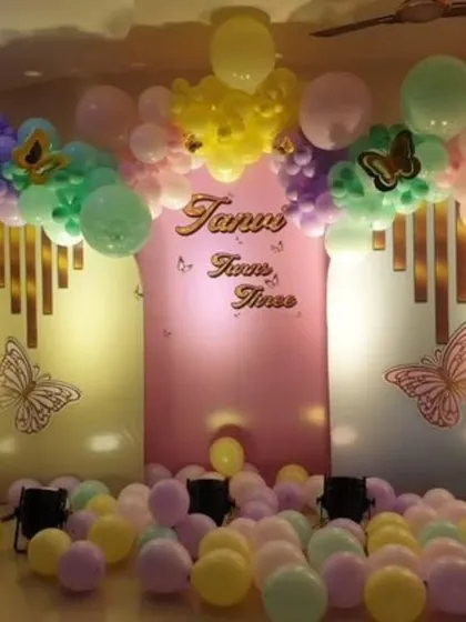 A butterfly-themed party with a pastel balloon arch and a soft pink backdrop. The floor is covered with balloons, creating a fun play area for the little ones.