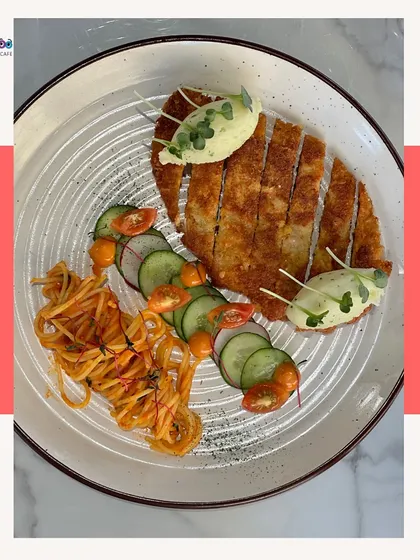 A crispy chicken schnitzel served with a side of pasta and fresh salad. A hearty and delicious meal.