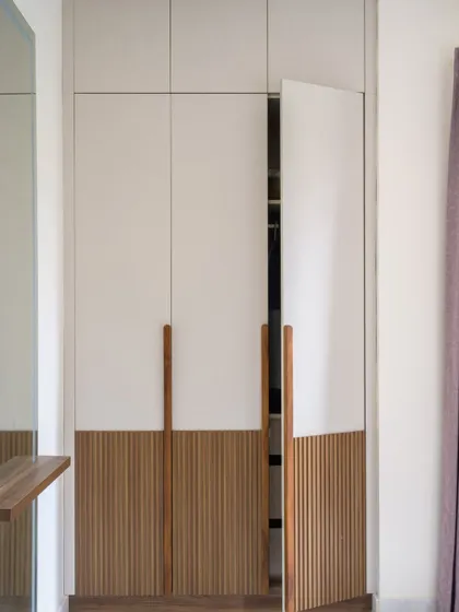 A detail of the custom wardrobe in the grandfather's room at 'Villa Calmora'. The fluted walnut shutters and long wooden handles add warmth and texture to the space.