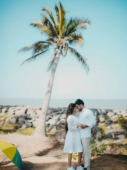 A beautiful pre-wedding portrait with a couple standing under a single palm tree on the beach.
