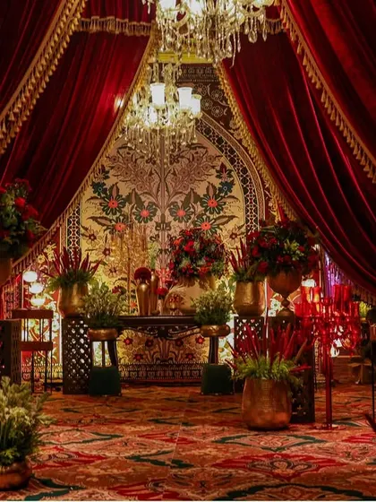 A wider view of the same floral entryway, showcasing the rich textures of the carpet, velvet drapes, and brass floral urns. The entire scene is an ode to timeless abundance.