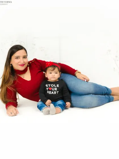 A mother and her baby lie on the floor in a casual, loving pose. The baby's "Stole Your Heart" shirt adds a touch of humor and sweetness.