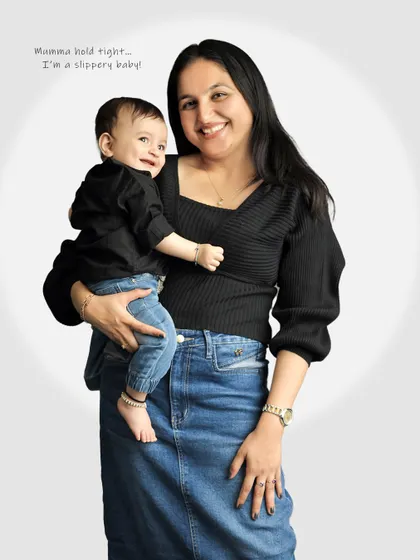 A mother holds her smiling baby, both looking happy and relaxed. This is a beautiful, classic mother-child portrait.