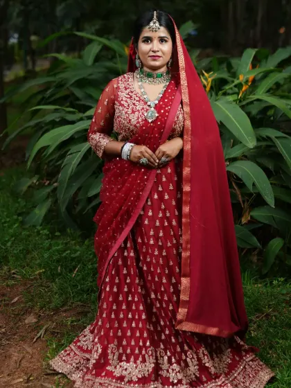 A full view of a Bollywood-inspired bridal look. The bride is wearing a layered emerald and AD necklace set that I styled to match her stunning red lehenga.