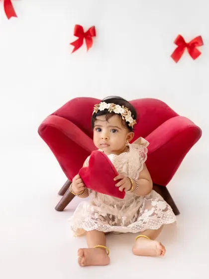 A sweet baby girl holding a red heart, perfect for a Valentine's Day themed photoshoot.