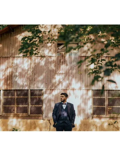 A stylish portrait of the groom in a rustic, industrial setting. The play of light and shadow adds a moody and dramatic effect.