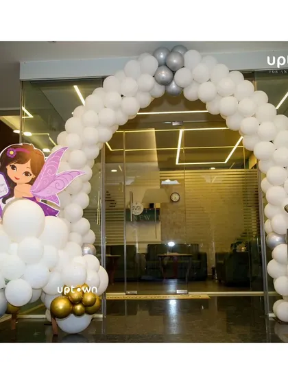 A grand entrance arch made of white and silver balloon's with a fairy cutout to welcome guests.