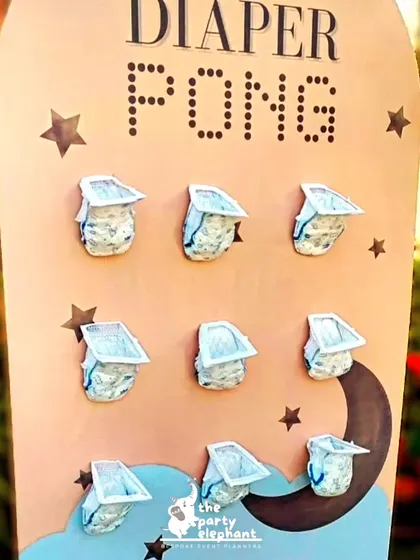 A close-up of the 'Diaper Pong' game, showing the small diapers attached to the board, ready for a fun and competitive game among the baby shower guests.