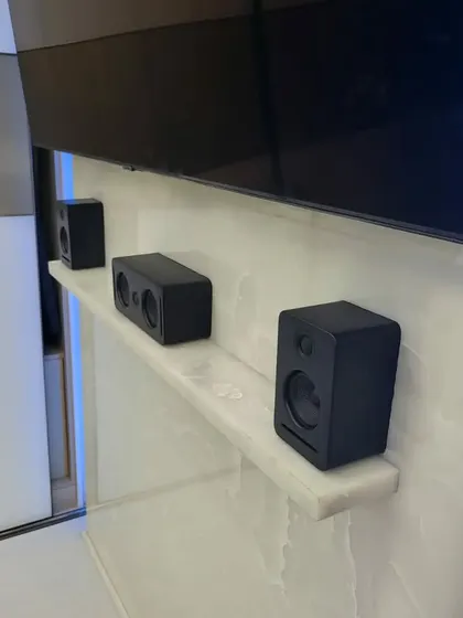 This photo shows the front speaker arrangement from the same Banashankri project. The center, left, and right channel speakers sit neatly on a shelf below the television, providing a clean, clutter-free look. Notice the absence of a bulky AVR box, which is a key benefit of this modern plug-and-play system.