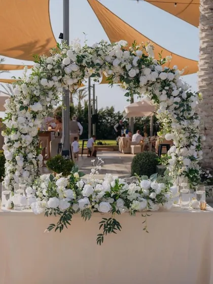 A circular floral arch on a tabletop. This is a beautiful alternative to a full-sized arch, perfect for decorating a welcome table or a bar.