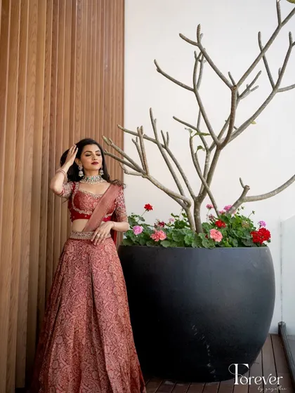 A modern, minimalist background puts the focus entirely on the bride and her stunning red lehenga and classic makeup.