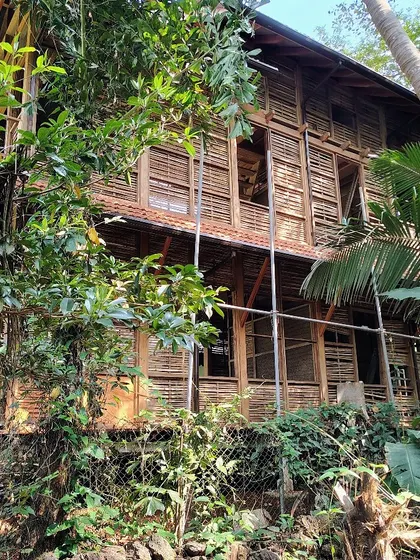 The intricate wooden framework and woven panels of the Moira cottage are visible here. The entire structure is designed to be lightweight and responsive to its environment, nestled among the trees.