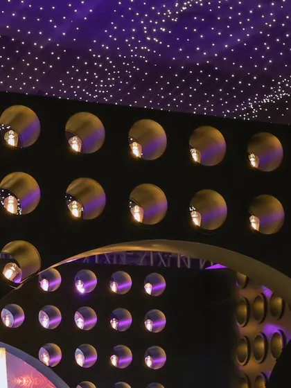 The curved, illuminated wall behind the bar, creating a visually stunning backdrop that enhances the high-energy party atmosphere.