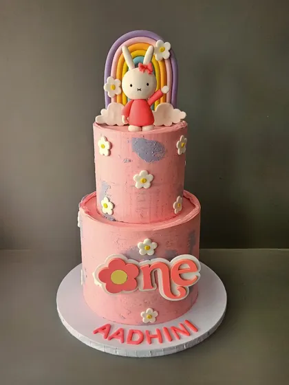Say hello to Miffy! This two-tier cake for Aadhini's first birthday features the adorable bunny Miffy, along with a pastel rainbow and cute floral details.
