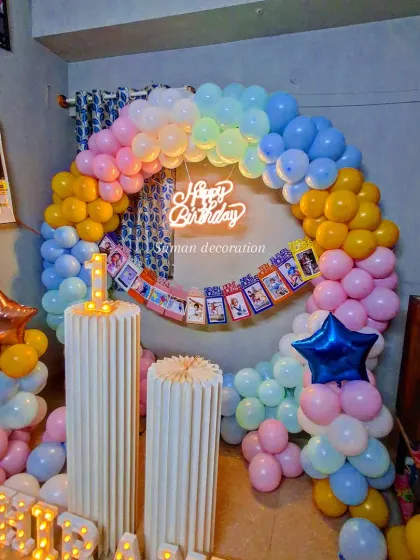 A full view of the pastel rainbow balloon ring setup for a first birthday in a home setting.