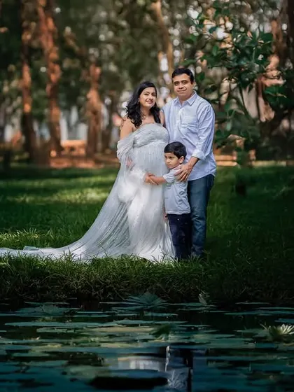 A complete family portrait, with their son, set against a beautiful lily pond. This wide shot captures the scale of nature and the love that fills this growing family.