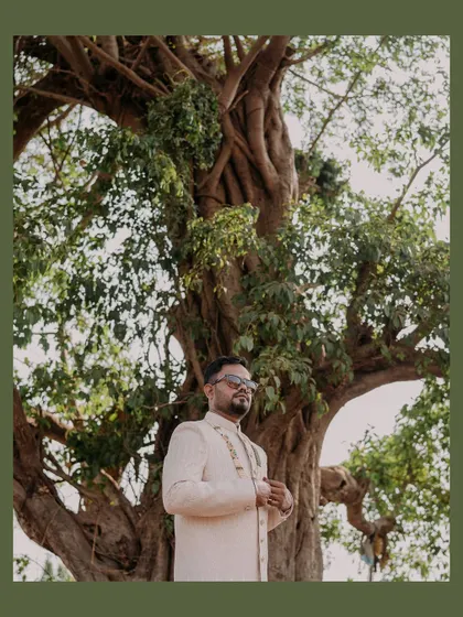 A creative portrait of the groom standing under a large, majestic tree. I use natural elements to create unique and memorable shots.