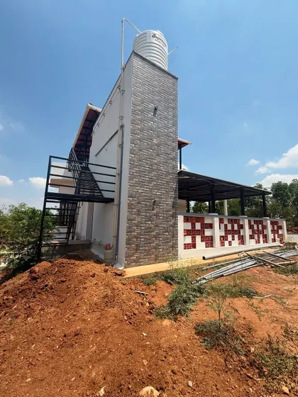 This image details the side of the house, featuring a stone-clad exterior wall that houses the water tank. We believe in integrating functional elements like plumbing and storage seamlessly into the architectural design.