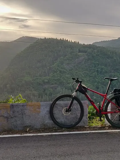 A mountain bike parked at a viewpoint, looking out over the incredible valley views of the Shevaroy hill range. This is the perfect reward after a challenging climb.
