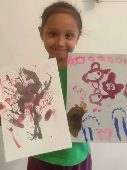 A duplicate image of a student displaying two of her creations, including an abstract cherry blossom tree.