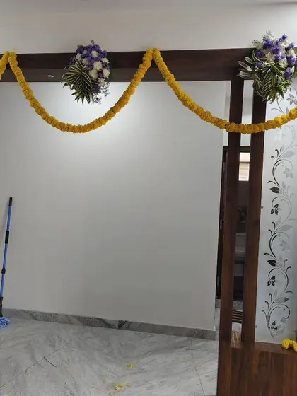 Simple flower bouquets placed on a wooden partition, along with a marigold garland.