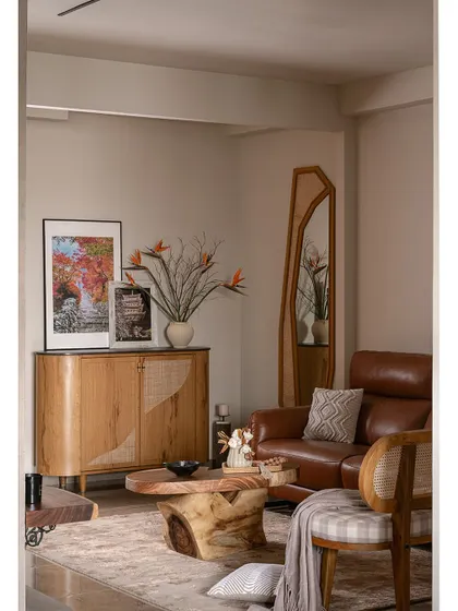 This view shows the foyer's shoe rack with rustic veneer and cane shutters, adding warmth and texture. An organic-shaped mirror enhances the sense of space, making the entryway feel more open and inviting.