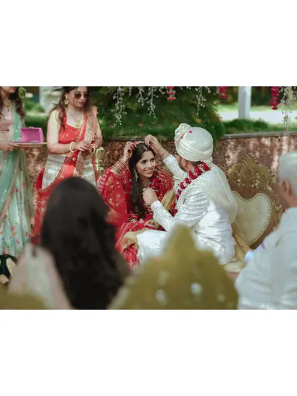 A groom places the 'maang tikka' on his bride, a significant and beautiful moment in their wedding ceremony. I help create a calm atmosphere for these important rituals.