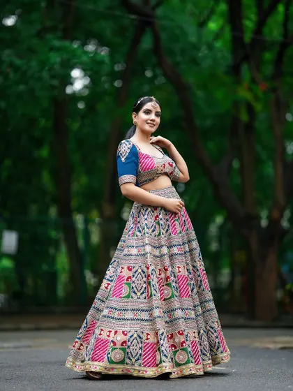 A three-quarter shot of the model in a patterned lehenga, set against a soft, natural background that highlights the outfit's colors.