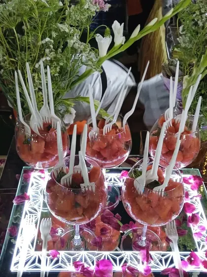 Individual portions of watermelon feta salad served in wine glasses on an illuminated tray, a modern and elegant serving style.