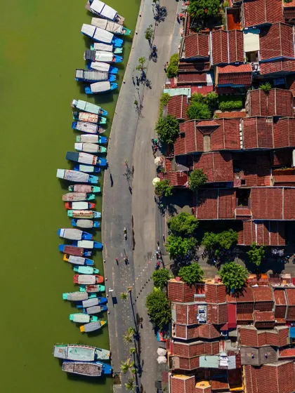 A top-down view of the ancient town of Hoi An, with its iconic yellow walls and traditional architecture, situated by the river.