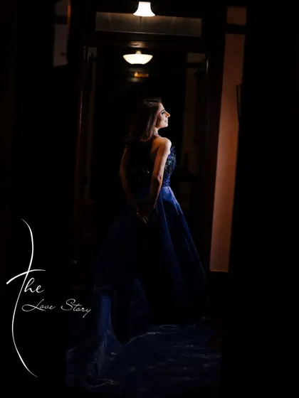 A moody and artistic portrait of the bride in a dark hallway. The dramatic lighting highlights her silhouette and the elegance of her gown.