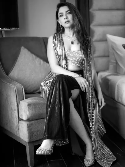 A seated portrait in black and white, conveying a sense of elegance and confidence. The lighting creates beautiful contrasts, highlighting the details of her attire.