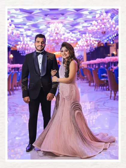 A classic, full-length portrait of the couple at their reception. The grand ballroom with its sea of chandeliers creates a breathtakingly opulent background.