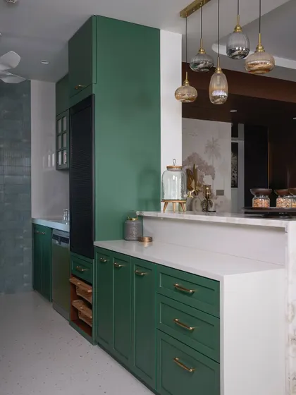 A wide shot of the green kitchen, highlighting the deep green cabinetry, open shelving for easy access, and the elegant pendant lights above the breakfast counter.