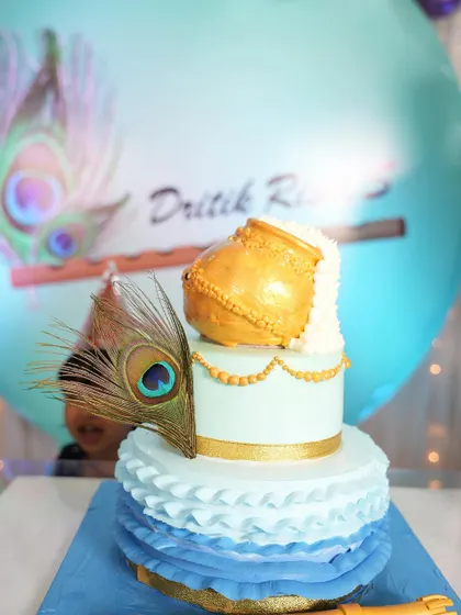The details matter in a themed shoot. This cake, with its peacock feather and golden pot, was the centerpiece of the Krishna-themed first birthday setup I created.
