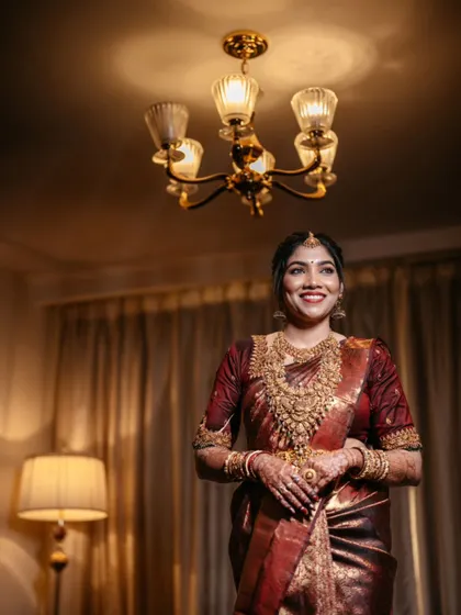 A radiant bridal portrait, her happy smile captured under the warm glow of a chandelier.