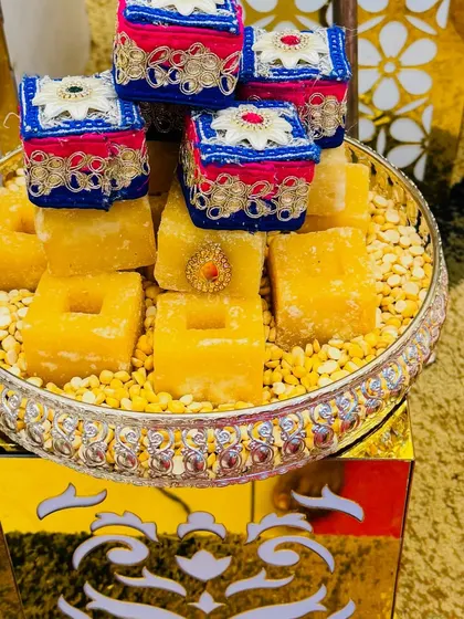 A platter of Mysore Pak decorated with tiny ornate boxes. This is a creative way to present traditional sweets for a wedding or festive occasion.