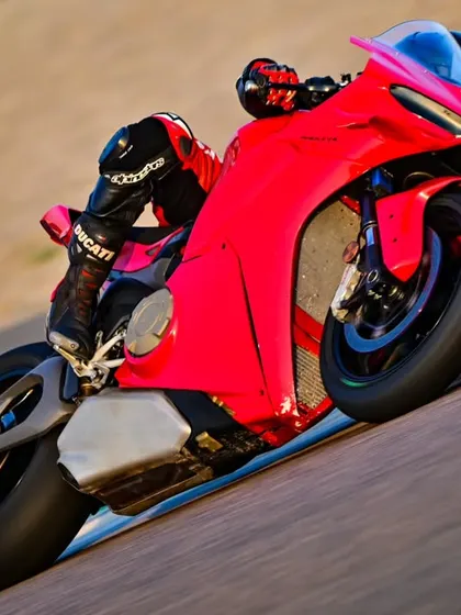 A close-up shot of a Ducati Panigale V4 at full lean, showcasing the rider's perfect form and the bike's performance capabilities.