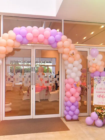 This butterfly-themed entrance combines a beautiful balloon arch with a personalized welcome board. The pastel colors and floral arrangement on the easel create a lovely first impression.