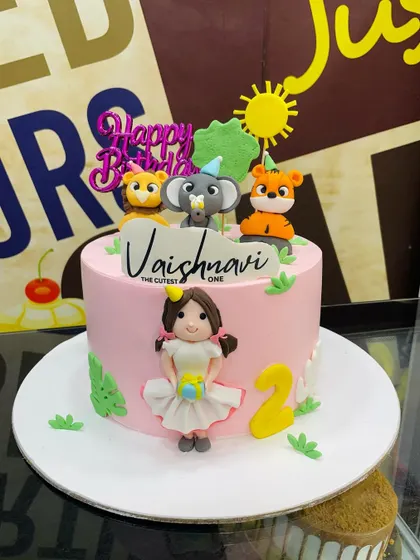 A sweet pink 3kg cake for a second birthday, featuring a fondant girl figurine alongside cute animal toppers.