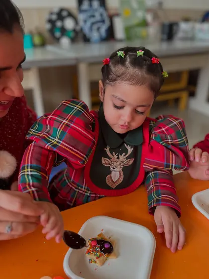 A mother and child share a moment while decorating a Christmas treat together.