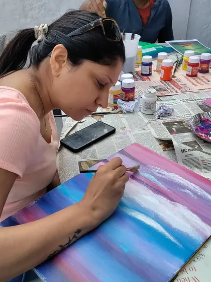 The process of creating clouds. This artist is adding layers of white to her colourful sky, a key step in landscape painting.