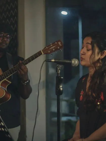 A beautiful moment between a vocalist and guitarist during an acoustic set. The soft lighting and intimate setting are perfect for soulful music.