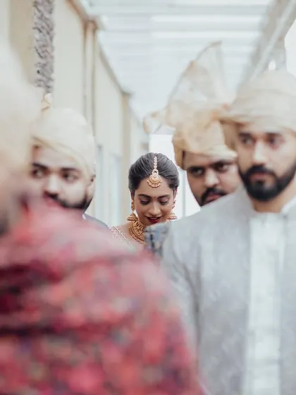 A creative shot of the bridal entry, with the bride framed by her brothers and family, her face the focal point in a sea of turbans.
