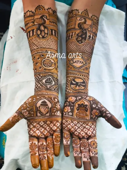This custom bridal henna features a variety of meaningful symbols. You can see a Ganesha for blessings, a peacock for beauty, and the couple's names hidden within the intricate patterns.