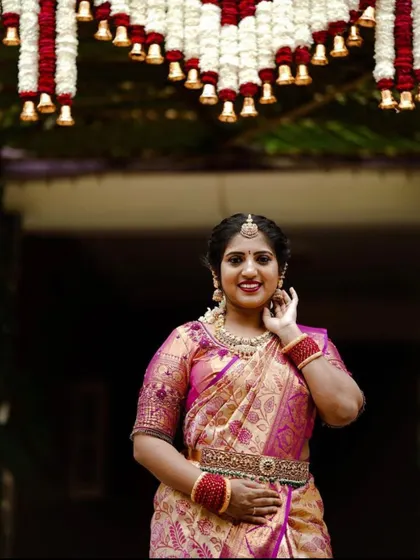 The bride is all smiles under our traditional wedding decor. The intricate floral hangings with red and white patterns are a specialty for South Indian weddings.