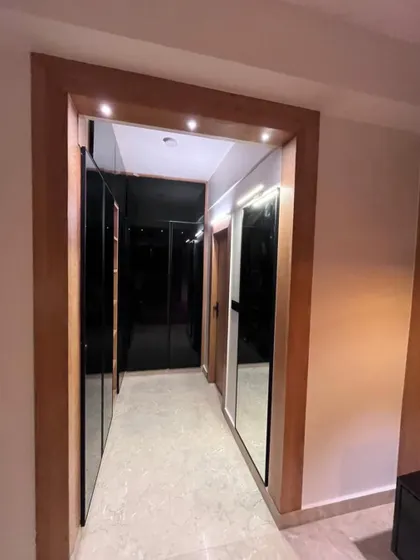 A view down a hallway featuring a custom walk-in closet. The combination of wood framing and black glass doors creates a sleek and modern passage, leading to the private spaces of the home.